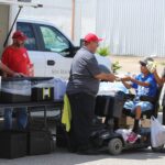 Canteen crew distributes water to man on scooter